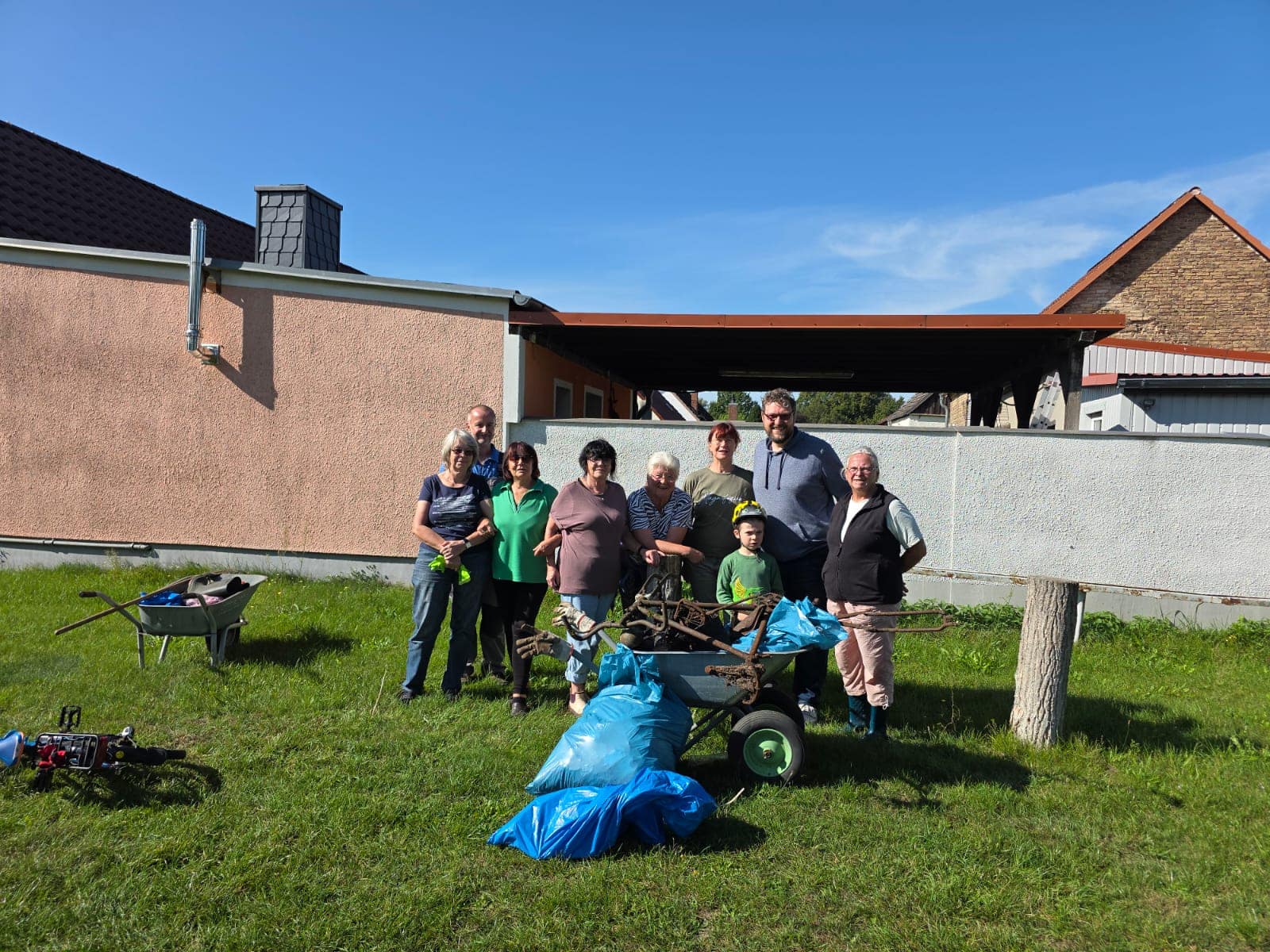Gruppenfoto CleanUp Day Frankendorf vor dem Gemeindehaus mit Müllsäcken und Schubkarre